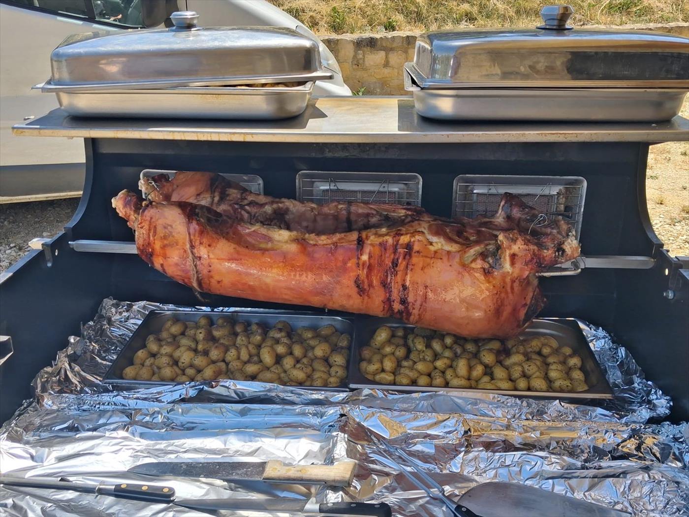 Cochon entier à la broche au-dessus d'un bac de pommes de terre