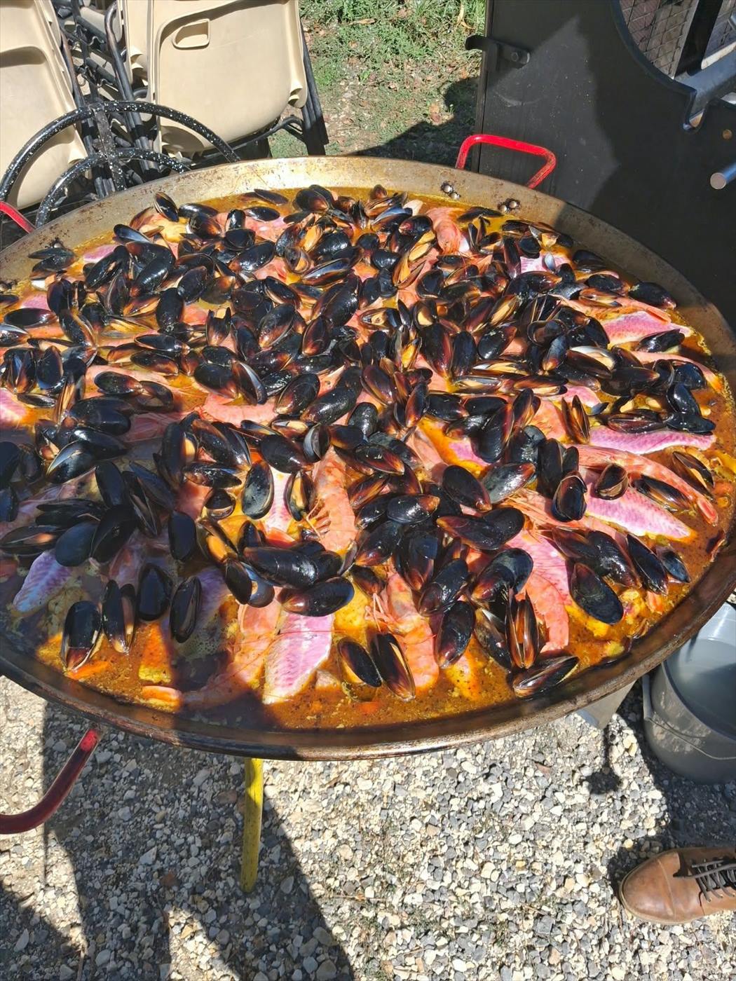 Grande poêle de riz au saumon et aux moules, cuisinée sur place
